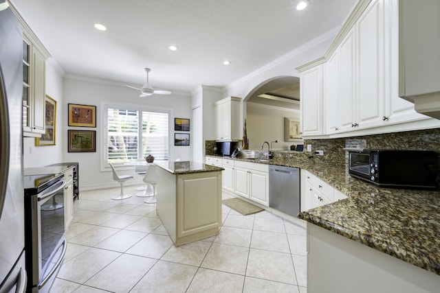 kitchen with ornamental molding, light tile patterned floors, appliances with stainless steel finishes, and a sink