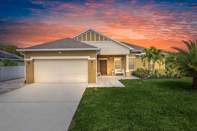 view of front facade with a garage, concrete driveway, fence, a yard, and stucco siding