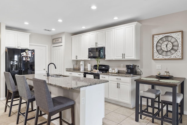 kitchen featuring light stone counters, recessed lighting, a sink, and black appliances