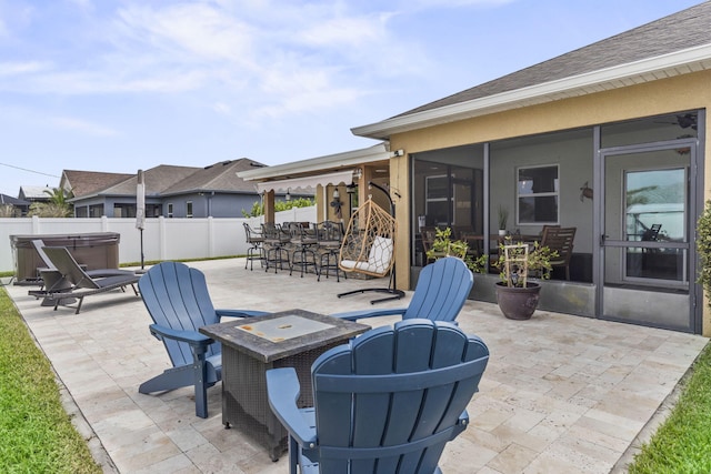 view of patio / terrace with a fire pit, fence, a sunroom, outdoor dining space, and a hot tub