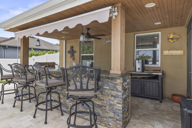 view of patio with a ceiling fan, fence, and outdoor dry bar