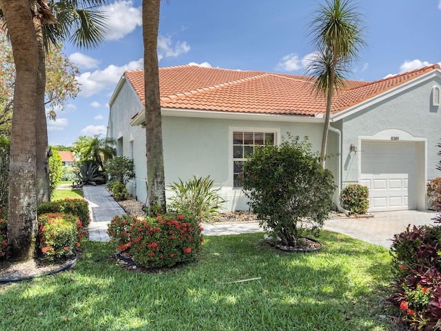 8389 Logia Cir, Boynton Beach, FL 33472 - view of front of home with stucco siding, driveway, an attached garage, a front lawn, and a tiled roof