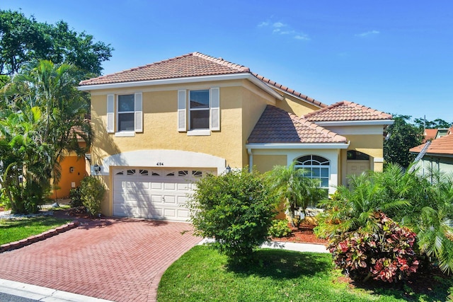 mediterranean / spanish-style home featuring a garage, a tile roof, decorative driveway, and stucco siding