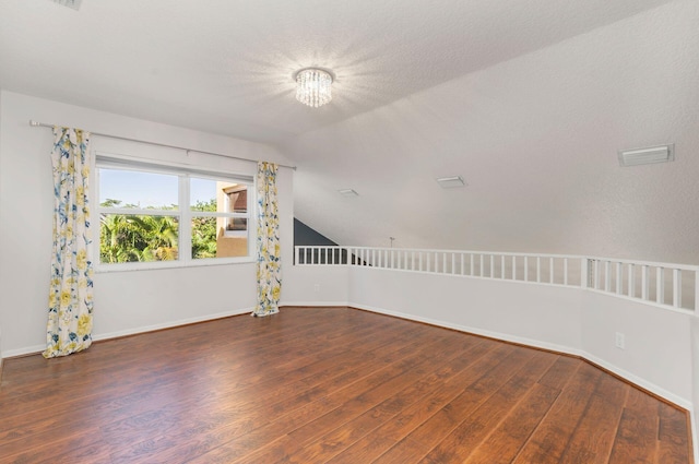 spare room featuring visible vents, baseboards, vaulted ceiling, and hardwood / wood-style floors