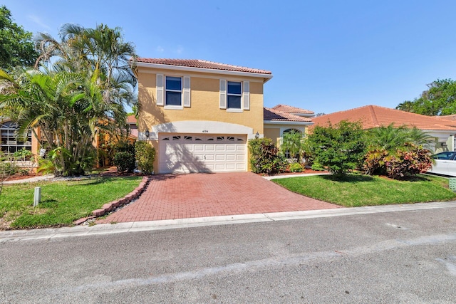 mediterranean / spanish-style house featuring a garage, a tiled roof, decorative driveway, stucco siding, and a front yard