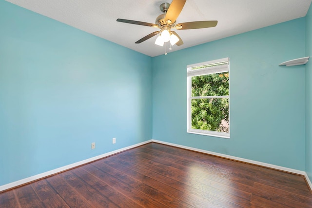 empty room with wood finished floors, a ceiling fan, and baseboards