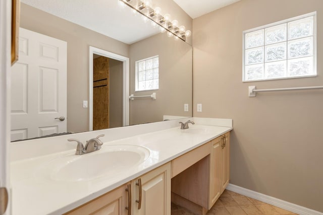 full bathroom featuring tile patterned flooring, a sink, baseboards, and double vanity