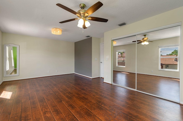 empty room featuring visible vents, a textured ceiling, baseboards, and hardwood / wood-style flooring