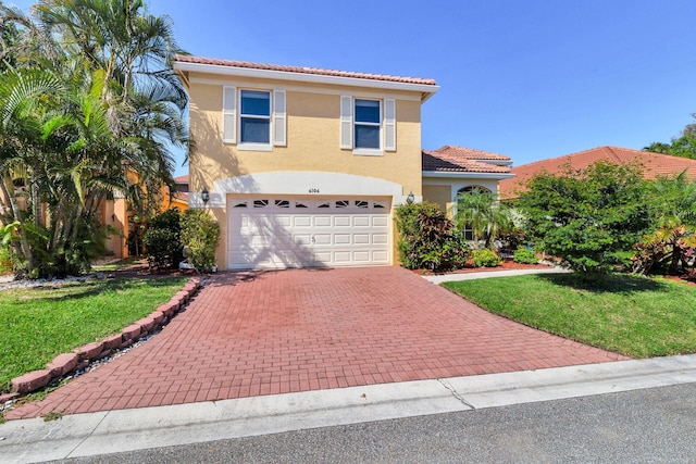 view of front facade with a tiled roof, decorative driveway, a front yard, and stucco siding