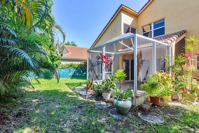 view of yard with glass enclosure and fence