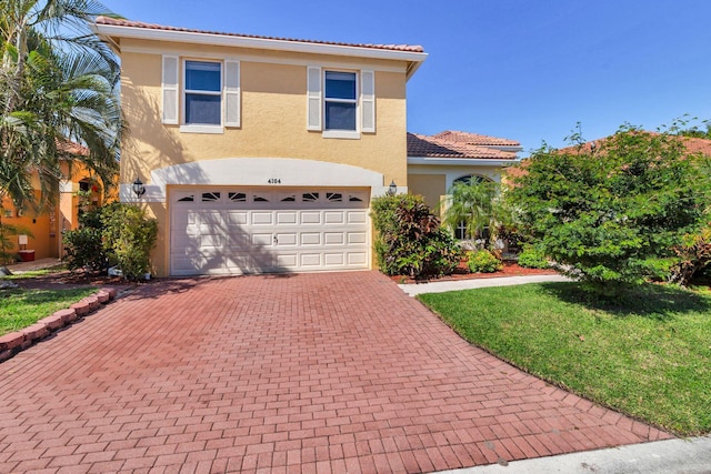 view of front of house featuring a garage, a tile roof, decorative driveway, a front lawn, and stucco siding