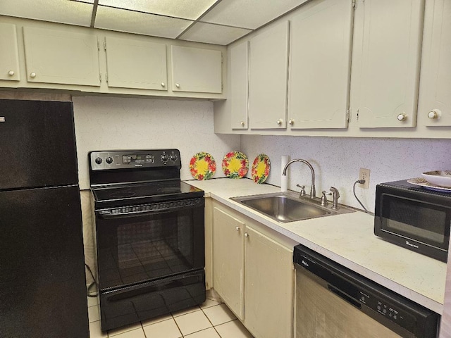 kitchen featuring light tile patterned floors, a drop ceiling, light countertops, black appliances, and a sink