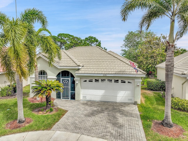 ranch-style home featuring decorative driveway, stucco siding, a garage, a tiled roof, and a front lawn