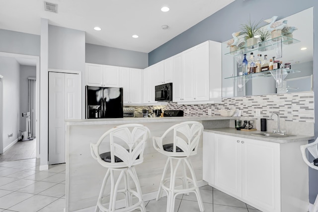 kitchen with visible vents, a sink, black appliances, and light tile patterned floors