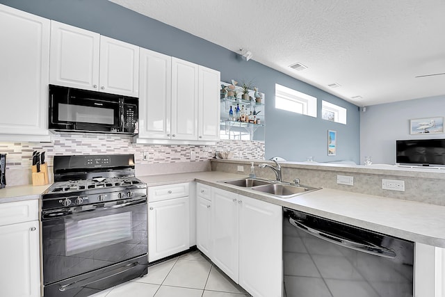 kitchen featuring a peninsula, a sink, visible vents, decorative backsplash, and black appliances