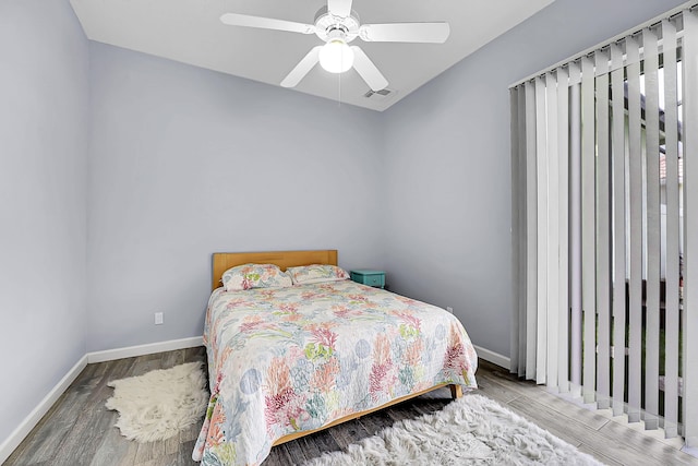 bedroom with baseboards, wood finished floors, visible vents, and ceiling fan