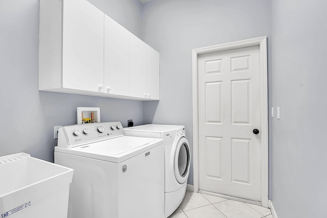 washroom featuring light tile patterned floors, a sink, washing machine and clothes dryer, baseboards, and cabinet space