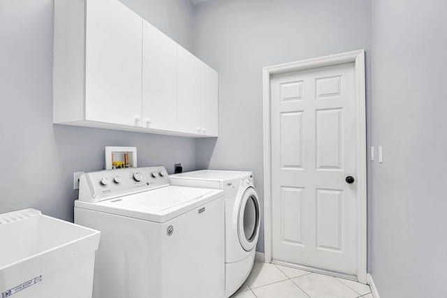 clothes washing area featuring light tile patterned flooring, cabinet space, a sink, and separate washer and dryer