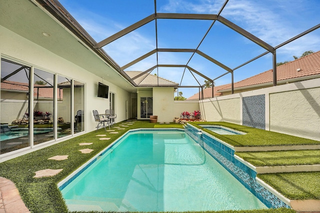 view of pool with a yard, a pool with connected hot tub, a patio area, and glass enclosure