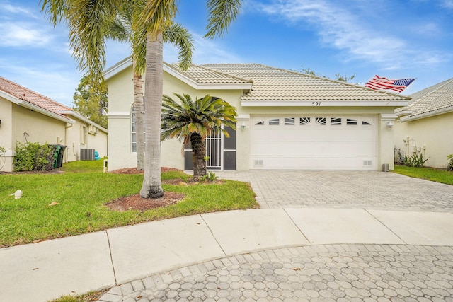 view of front facade featuring cooling unit, a garage, decorative driveway, stucco siding, and a front lawn