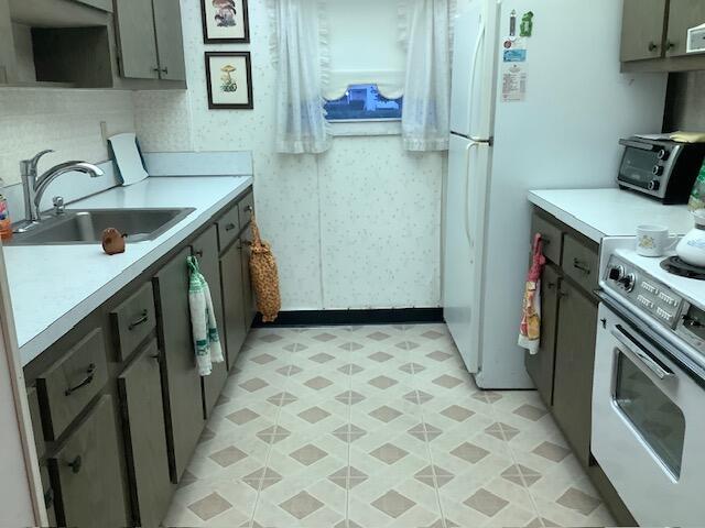 kitchen featuring a toaster, light countertops, a sink, and electric range oven