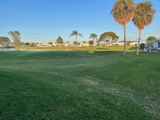 surrounding community with a water view and a lawn