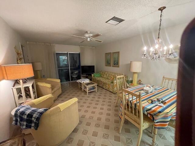 living room with ceiling fan with notable chandelier, a textured ceiling, and visible vents