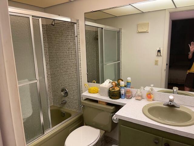 bathroom featuring enclosed tub / shower combo, toilet, and vanity