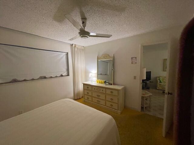 bedroom featuring a ceiling fan, light colored carpet, and a textured ceiling