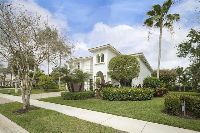 view of front facade featuring stucco siding, decorative driveway, and a front yard