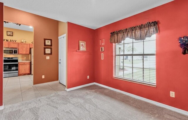spare room featuring light tile patterned floors, baseboards, and light colored carpet