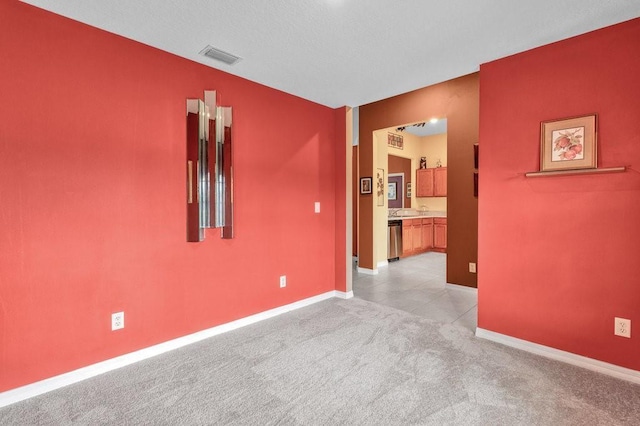 empty room featuring light carpet, visible vents, and baseboards