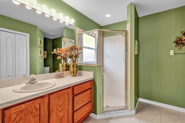 bathroom featuring a textured ceiling, tile patterned flooring, vanity, baseboards, and a stall shower