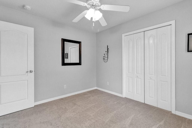 unfurnished bedroom with ceiling fan, a closet, baseboards, and carpet flooring