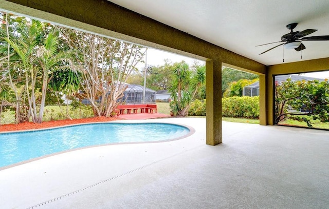 pool featuring glass enclosure, ceiling fan, and a patio area
