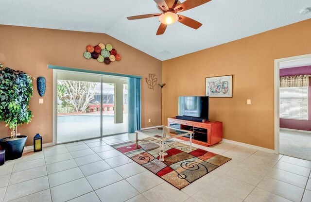 tiled living area featuring vaulted ceiling, a ceiling fan, and baseboards