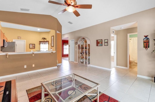 living room with light tile patterned floors, ceiling fan, visible vents, and vaulted ceiling