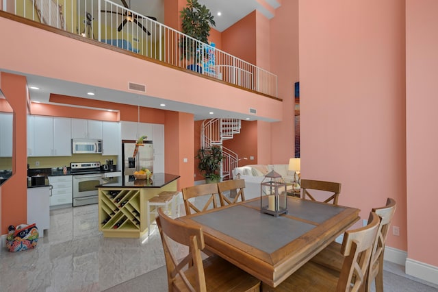 dining space featuring stairs, a high ceiling, visible vents, and baseboards