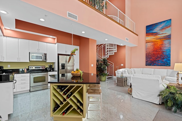 kitchen with a kitchen breakfast bar, white cabinets, marble finish floor, appliances with stainless steel finishes, and dark countertops