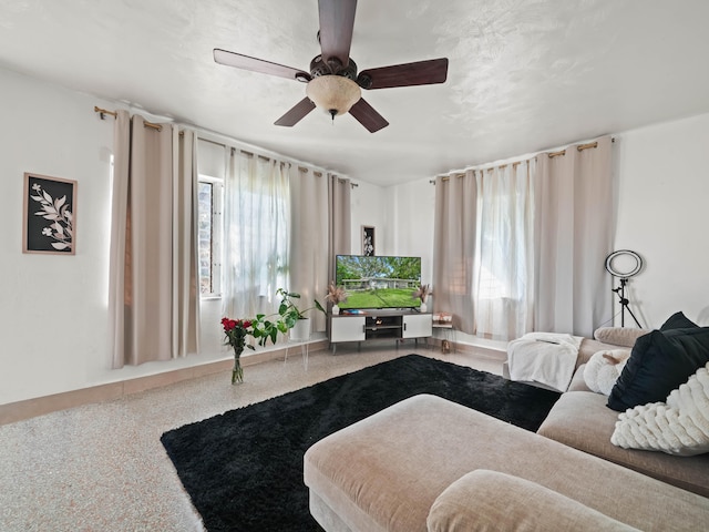 living area with a ceiling fan, plenty of natural light, and speckled floor