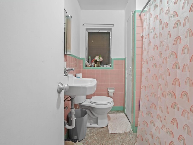 bathroom with a wainscoted wall, tile walls, toilet, a shower with curtain, and speckled floor