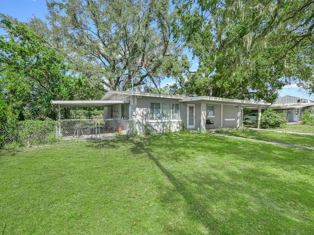 ranch-style house featuring an attached carport, fence, and a front lawn