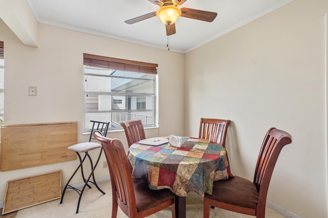 carpeted dining area with a ceiling fan, baseboards, and ornamental molding