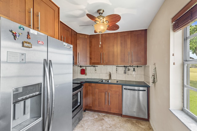 kitchen featuring a sink, dark countertops, appliances with stainless steel finishes, brown cabinetry, and decorative backsplash