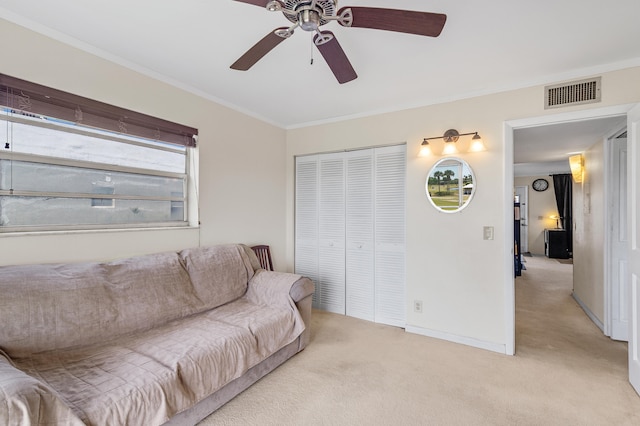 living area with visible vents, light carpet, ornamental molding, baseboards, and ceiling fan