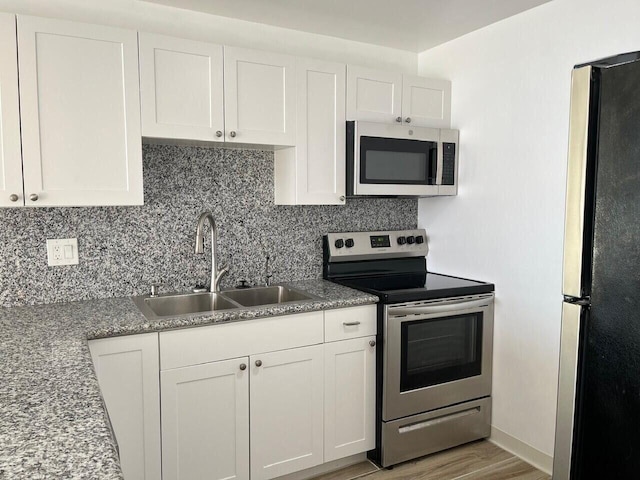 kitchen featuring decorative backsplash, appliances with stainless steel finishes, light wood-style floors, white cabinets, and a sink