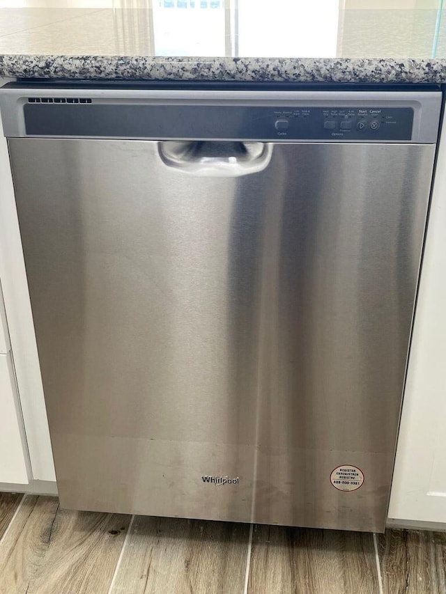 details with stainless steel dishwasher, wood finished floors, and white cabinetry