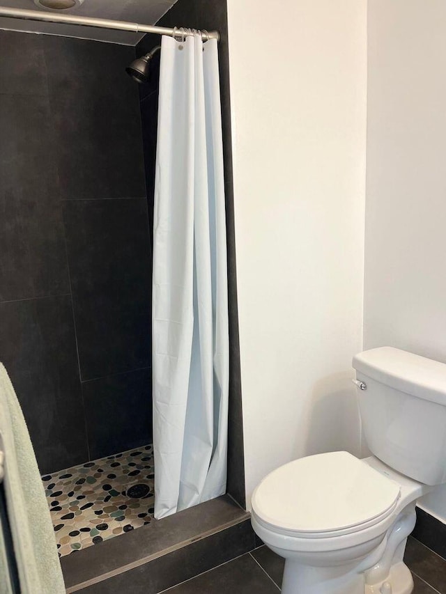 full bathroom featuring a shower stall, toilet, and tile patterned floors