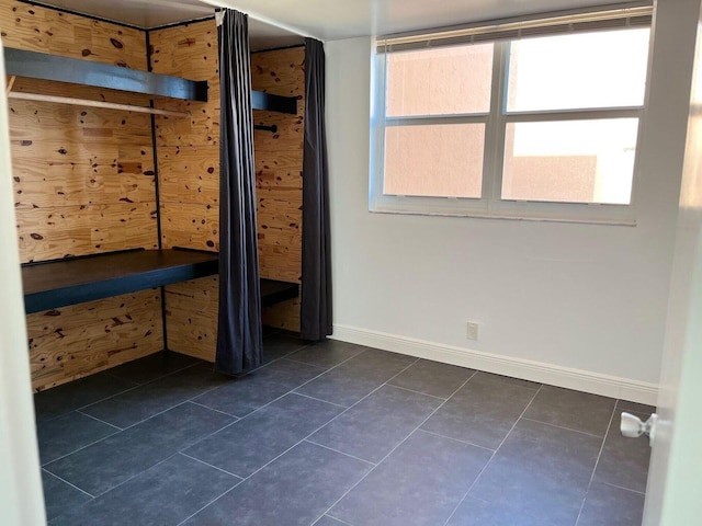 unfurnished bedroom featuring dark tile patterned floors and baseboards