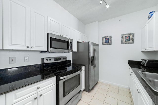 kitchen featuring a toaster, light tile patterned floors, stainless steel appliances, white cabinetry, and a sink